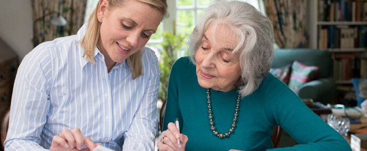 elderly woman signing some documents