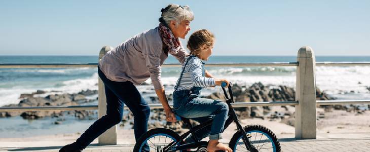 Grandmother teaching her granddaughter how to ride a bicycle