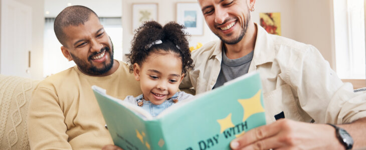 Gay couple reading a book with their child