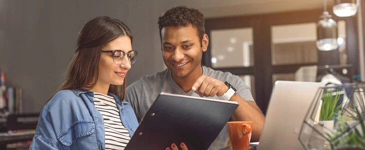 A young man and woman, both looking at a clipboard