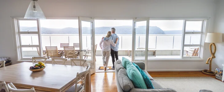 Elderly couple looking out of the balcony of their beach-side house