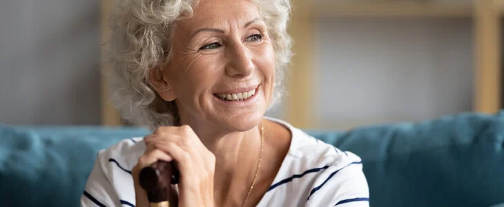 elder woman smiling and holding a cane