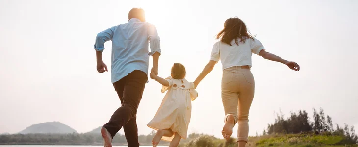 Young family and child running into the sunset