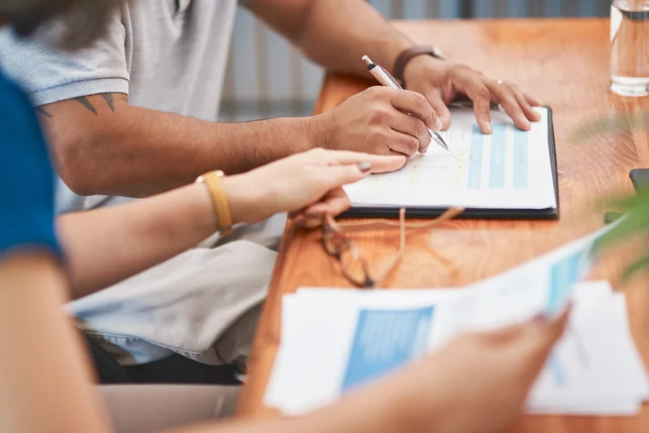 Two people reviewing documents at a wooden table.